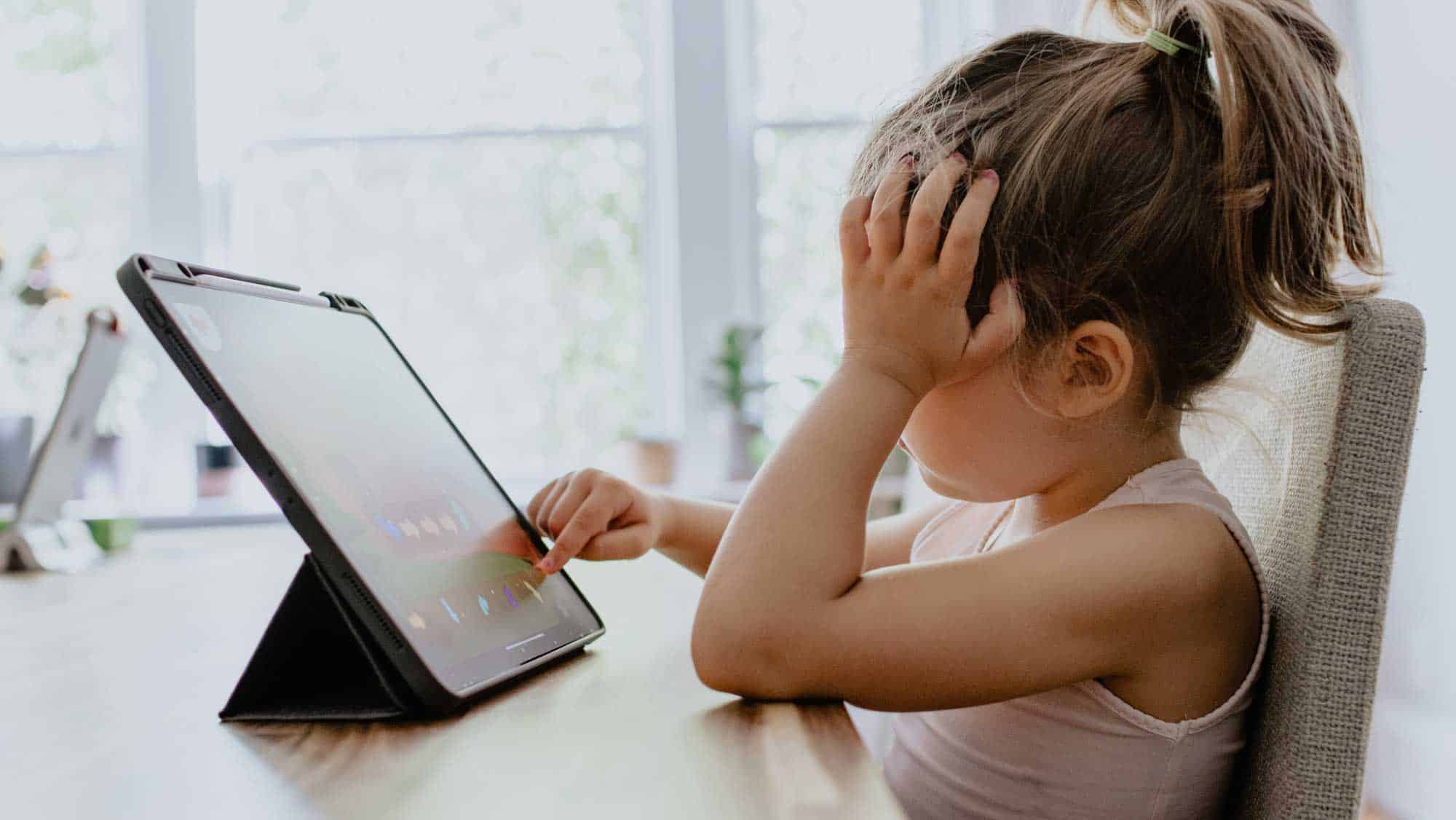 Little girl looking bored at a screen - the mental health impact of Covid-19